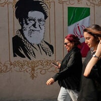 Women walk past a portrait of the late Iranian supreme leader Ayatollah Ali Khamenei, who was killed in US-Israel strikes on February 28, and images of the Iranian flag, on a sidewalk in downtown Tehran, Iran, August 20, 2026. (AP Photo/Vahid Salemi)