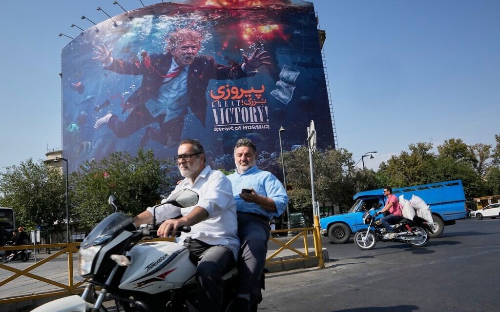 Motorcyclists pass a billboard depicting US President Donald Trump underwater amid explosions, with the words 'Great Victory! Strait of Hormuz,' in Tehran, Iran, August 24, 2026. (AP/Vahid Salemi)