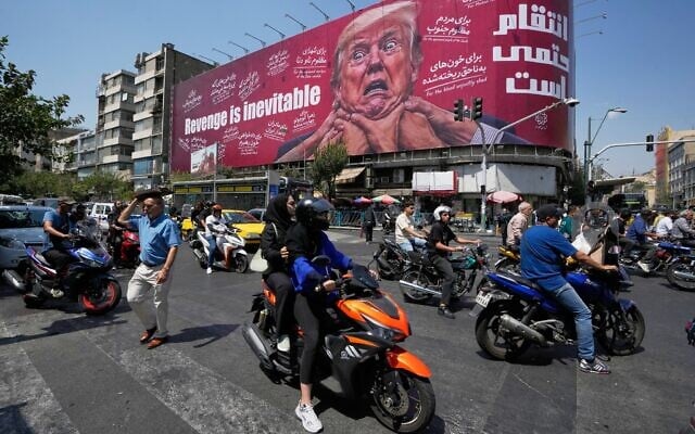 Motorcyclists pass a billboard depicting US President Donald Trump with hands around his neck beneath the words 'Revenge is inevitable' in Tehran, Iran, August 24, 2026. (AP Photo/Vahid Salemi)