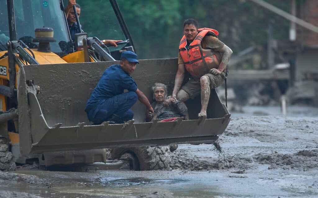 Rescuers use an earthmover to carry a victim of flash flooding to safety along the Trishuli River in Nepal’s Nuwakot district, August 26, 2026. (AP Photo/Niranjan Shrestha)