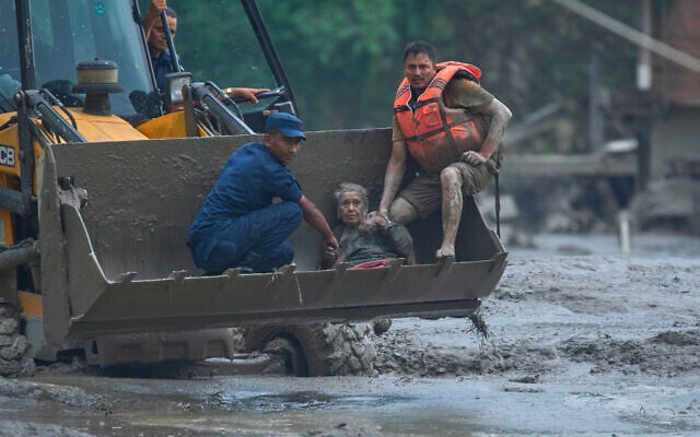 Rescuers use an earthmover to carry a victim of flash flooding to safety along the Trishuli River in Nepal’s Nuwakot district, August 26, 2026. (AP Photo/Niranjan Shrestha)