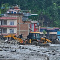 Rescuers use earthmovers to reach submerged houses after flash flooding along the Trishuli River in Nepal’s Nuwakot district, August 26, 2026. (AP Photo/Niranjan Shrestha)