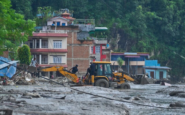 Rescuers use earthmovers to reach submerged houses after flash flooding along the Trishuli River in Nepal’s Nuwakot district, August 26, 2026. (AP Photo/Niranjan Shrestha)