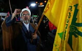 A cleric in Iran chants a slogan as he holds a flag of Lebanon’s Hezbollah during a pro-government gathering in Tehran, August 26, 2026. (AP Photo/Vahid Salemi)