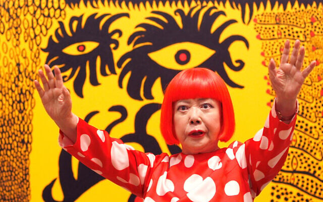 Japanese artist Yayoi Kusama poses for photographers in front of her painting “Love Arrives at the Earth Carrying with it a Tale of the Cosmos” at the Tate Modern in London, on February 7, 2012. (AP Photo/Kirsty Wigglesworth)