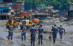 Nepalese policemen watch as earthmovers clear the debris of flash flooding in Nepal’s Nuwakot district, August 27, 2026. (AP Photo/Niranjan Shrestha)
