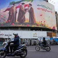 Motorbikes drive past a billboard depicting Iran’s late supreme leader Ayatollah Ali Khamenei, center, handing the country’s flag to his son and successor, Ayatollah Mojtaba Khamenei, right, as the late revolutionary founder Ayatollah Ruhollah Khomeini stands at left, in a square in downtown Tehran, Iran, March 10, 2026. (AP Photo/Vahid Salemi)