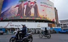 Motorbikes drive past a billboard depicting Iran’s late supreme leader Ayatollah Ali Khamenei, center, handing the country’s flag to his son and successor, Ayatollah Mojtaba Khamenei, right, as the late revolutionary founder Ayatollah Ruhollah Khomeini stands at left, in a square in downtown Tehran, Iran, March 10, 2026. (AP Photo/Vahid Salemi)