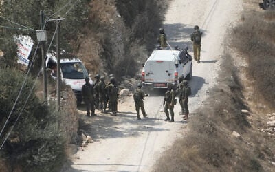 IDF soldiers secure a building under construction as ambulances evacuate injured Palestinians following an attack by settlers in the West Bank village of Qusra, August 29, 2026. (AP Photo/Majdi Mohammed)