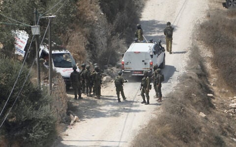 IDF soldiers secure a building under construction as ambulances evacuate injured Palestinians following an attack by settlers in the West Bank village of Qusra, August 29, 2026. (AP Photo/Majdi Mohammed)