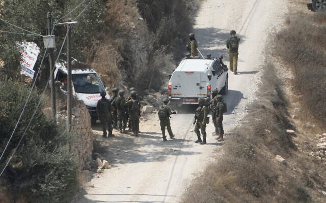 IDF soldiers secure a building under construction as ambulances evacuate injured Palestinians following an attack by settlers in the West Bank village of Qusra, August 29, 2026. (AP Photo/Majdi Mohammed)