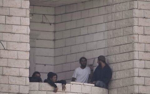Settlers who raided a Palestinian village gather on the balcony of a building under construction in the West Bank's Qusra, August 29, 2026. (AP Photo/Majdi Mohammed)