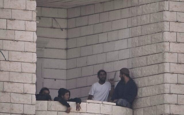 Settlers who raided a Palestinian village gather on the balcony of a building under construction in the West Bank's Qusra, August 29, 2026. (AP Photo/Majdi Mohammed)