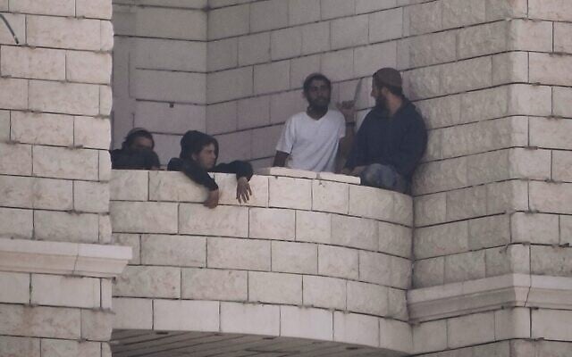 Settlers who raided a Palestinian village gather on the balcony of a building under construction in the West Bank's Qusra, August 29, 2026. (AP Photo/Majdi Mohammed)