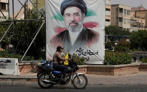 A man drives past a banner showing a portrait of the Iranian Supreme Leader Ayatollah Mojtaba Khamenei, in downtown Tehran, Iran, August 31, 2026. (AP Photo/Vahid Salemi)