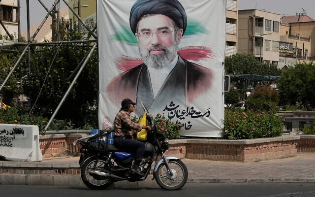 A man drives past a banner showing a portrait of the Iranian Supreme Leader Ayatollah Mojtaba Khamenei, in downtown Tehran, Iran, August 31, 2026. (AP Photo/Vahid Salemi)