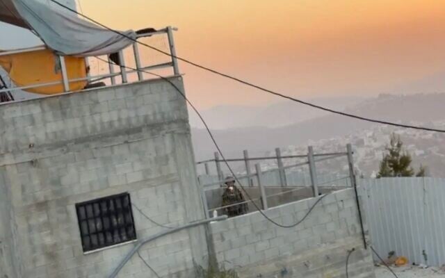 A screenshot of video in which Israeli troops toss clothes belonging to Palestinians from the window of a home in the West Bank village of Qusra, August 20, 2026. (X screenshot)