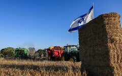 An Israeli flag flies over an agricultural field in the Gaza border community of Kibbutz Nahal Oz as members take part in traditional Shavuot celebrations, on May 22, 2026. (Tsafrir Abayov/Flash90)