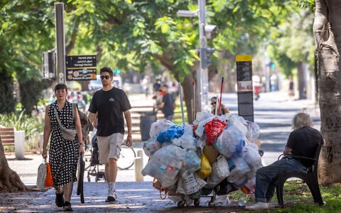 A homeless man sits on Rothschild Boulevard in Tel Aviv, July 28, 2026. (Miriam Alster/FLASH90)
