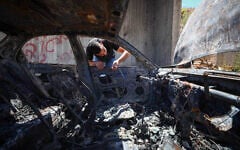 Illustrative: A Palestinian man inspects his burnt-out car after it was set alight by Israeli settlers, near Bethlehem, West Bank, on July 29, 2026. (Wisam Hashlamoun/FLASH90)