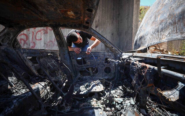 Illustrative: A Palestinian man inspects his burnt-out car after it was set alight by Israeli settlers, near Bethlehem, West Bank, on July 29, 2026. (Wisam Hashlamoun/FLASH90)