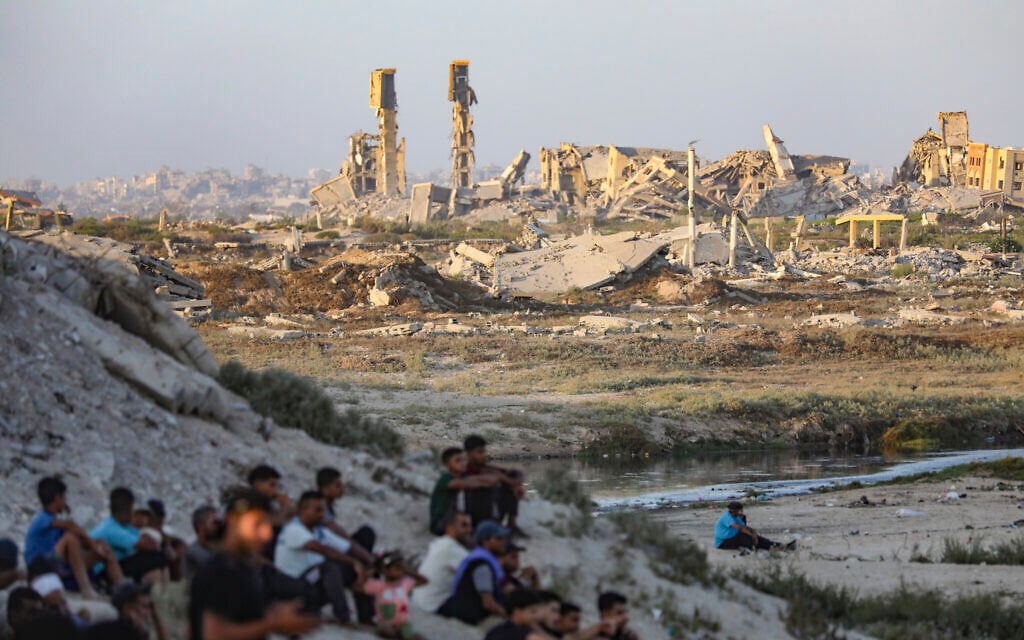 Palestinians seen near buildings destroyed during the recent war between Israel and Hamas, in Gaza City, central Gaza Strip, July 31, 2026. (Ali Hassan/Flash90)