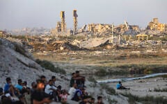 Palestinians seen near buildings destroyed during the recent war between Israel and Hamas, in Gaza City, central Gaza Strip, July 31, 2026. (Ali Hassan/Flash90)