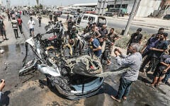Palestinians gather at the site of an Israeli strike on a vehicle on Salah al-Din Street in Deir al-Balah, central Gaza Strip, August 2, 2026. (Ali Hassan/Flash90)
