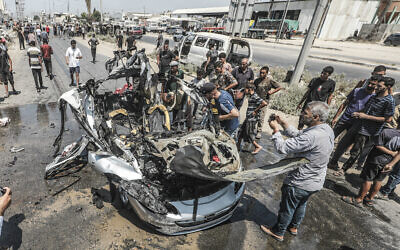 Palestinians gather at the site of an Israeli strike on a vehicle on Salah al-Din Street in Deir al-Balah, central Gaza Strip, August 2, 2026. (Ali Hassan/Flash90)