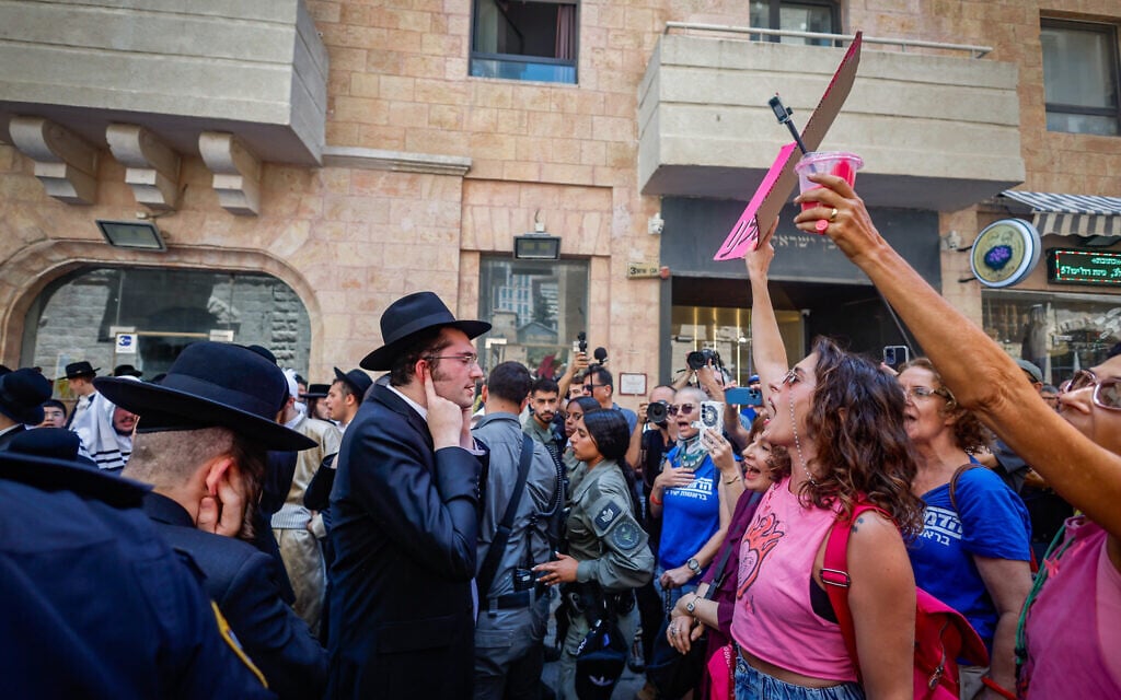 Haredi men protest outside the Basimta cafe for opening on Shabbat while secular counterprotesters stand in front of them, in Jerusalem on August 8, 2026. (Oren Ben Hakoon/Flash90)