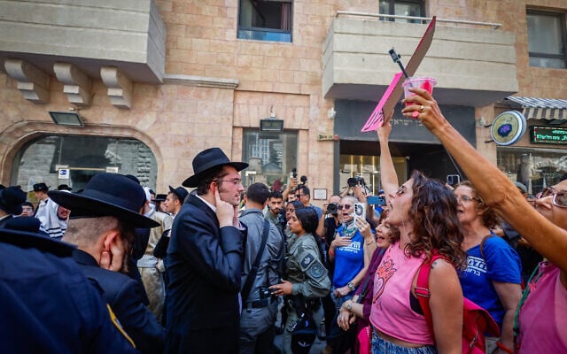 Haredi men protest outside the Basimta cafe for opening on Shabbat while secular counterprotesters stand in front of them, in Jerusalem on August 8, 2026. (Oren Ben Hakoon/Flash90)