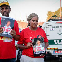 The parents of missing girl Haymanut Kasau seen protesting and holding her photo in Tel Aviv on August 12, 2026. (Avshalom Sassoni/Flash90)
