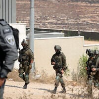 Troops seen outside homes that had been besieged by Israeli settlers in the village of Qusra in the West Bank, on August 14, 2026. (FLASH90)