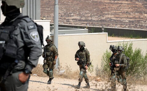 Troops seen outside homes that had been besieged by Israeli settlers in the village of Qusra in the West Bank, on August 14, 2026. (FLASH90)