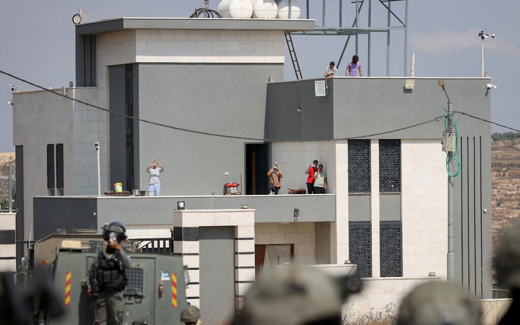 FILE: Israeli activists and Palestinian residents stand on the roof of a house besieged by Israeli settlers in the village of Qusra, south of Nablus, West Bank, on August 14, 2026. (FLASH90)
