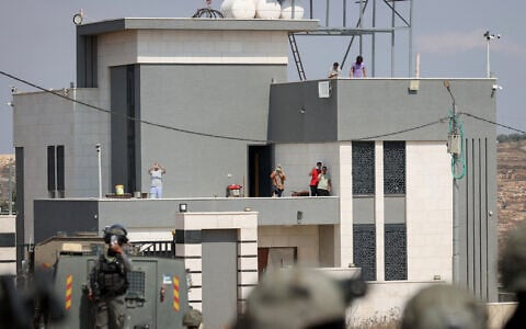 Israeli activists and Palestinian residents stand on the roof of a house besieged by Israeli settlers in the village of Qusra, south of Nablus, West Bank, on August 14, 2026. (FLASH90/ File)