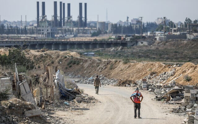 Palestinians walk past widespread destruction caused during the war with Israel in Al-Zahra City, central Gaza Strip, August 22, 2026. (Ali Hassan/Flash90)