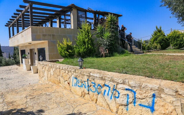 Palestinians inspect a house that was set on fire and spray-painted with graffiti during an attack by settler extremists in the village of Osarin, south of Nablus in the West Bank, August 23, 2026. (Nasser Ishtayeh/Flash90)