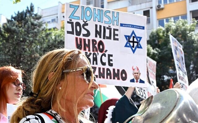 A woman beats a pot next to a placard reading 'Zionism is not dead yet, and we don't know when it will be,' at a pro-Palestinian, anti-Israel rally in Podgorica, Montenegro, September 14, 2025. (Photo by SAVO PRELEVIC / AFP)