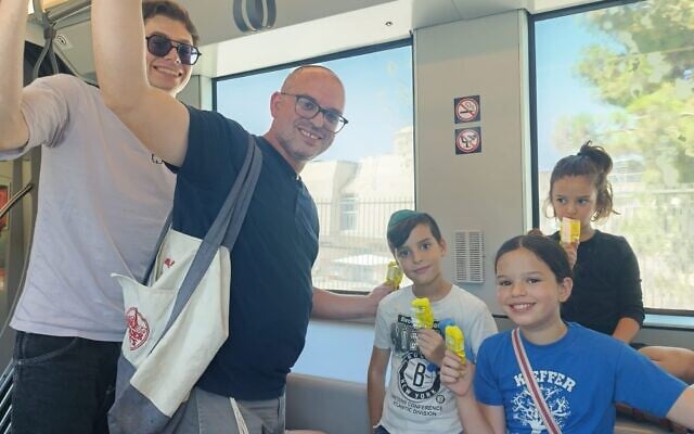 Daniel Ginsburg and his kids ride the new L3 light rail route, August 21, 2026 (Zev Stub/Times of Israel)