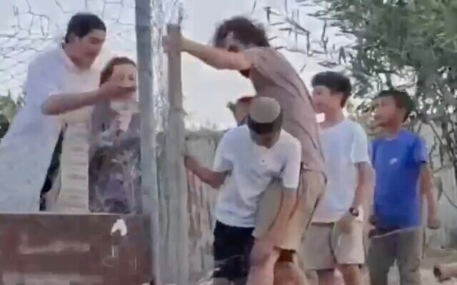 Activist identified as Finn Joughin uses his body to try and stop Israeli children crossing the fence into the southern West Bank's Umm al-Kheir on August 30, 2026 (Screen grab of video circulating on social media)