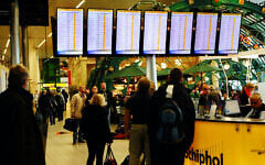 Illustrative: Passengers look at monitors displaying delayed and canceled flights at Schiphol International Airport near Amsterdam on November 4, 2013, after strong winds grounded and diverted aircraft. (Tom Gandolfini/AFP)