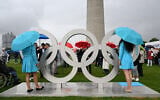 Hostesses and visitors stand next to Olympic Rings that were installed on the roof of the small Olympic Hall to mark the 50th anniversary of the 1972 Summer Olympics in Munich on July 1, 2022. (Christof STACHE/AFP)