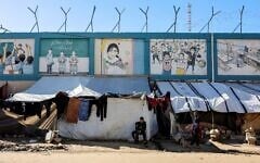 Displaced Palestinian families set-up their tent shelters in the vicinity of The United Nations Relief and Works Agency for Palestine Refugees in the Near East’s (UNRWA) headquarters sit on rubble from a destroyed building, in Gaza City on January 11, 2026. (Omar AL-QATTAA/AFP)