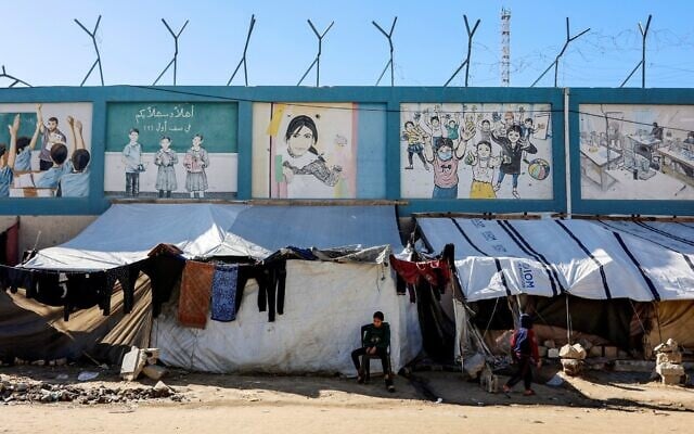 Displaced Palestinian families set-up their tent shelters in the vicinity of The United Nations Relief and Works Agency for Palestine Refugees in the Near East’s (UNRWA) headquarters sit on rubble from a destroyed building, in Gaza City on January 11, 2026. (Omar AL-QATTAA/AFP)