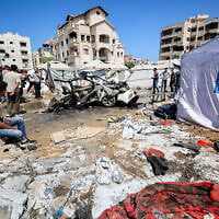 People gather near a destroyed vehicle following an Israeli strike in the Rimal neighborhood of Gaza City on September 1, 2026. (Omar AL-QATTAA/AFP)