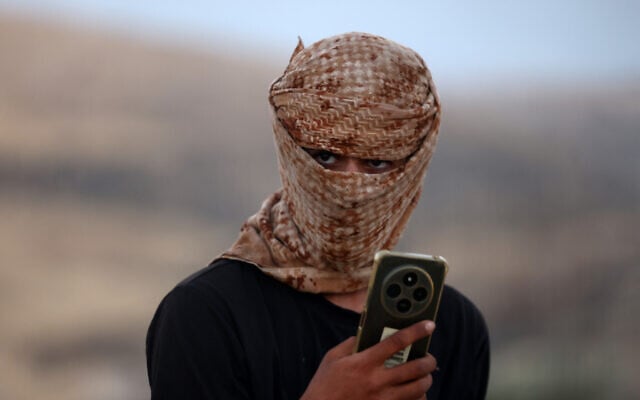 A masked Israeli settler stands near the Kaabneh Bedouin community, east of Taybeh, northeast of Ramallah, in the West Bank, on September 1, 2026. (Zain JAAFAR/AFP)
