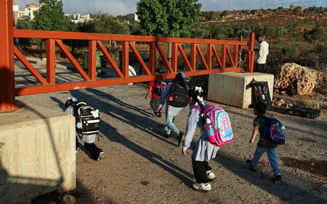 Palestinian students cross one of the gates erected at the entrance of the village of Qusra, south of the city of Nablus in the West Bank, on September 6, 2026, the first day of new academic year. (JAAFAR ASHTIYEH/AFP)