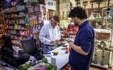 Iranian shop owner Morteza Asaadi (L) attends to a customer at his shop in downtown Bur Dubai on September 3, 2026. (Fadel Senna/AFP)