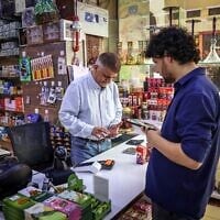 Iranian shop owner Morteza Asaadi (L) attends to a customer at his shop in downtown Bur Dubai on September 3, 2026. (Fadel Senna/AFP)